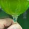 Bicchiere di olio extravergine nuovo 2026 controluce, verde smeraldo e limpido, nel frantoio di Farnese